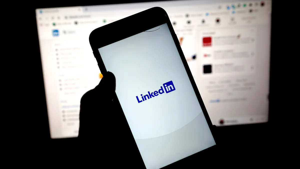 A person holds a phone loading the LinkedIn app.
