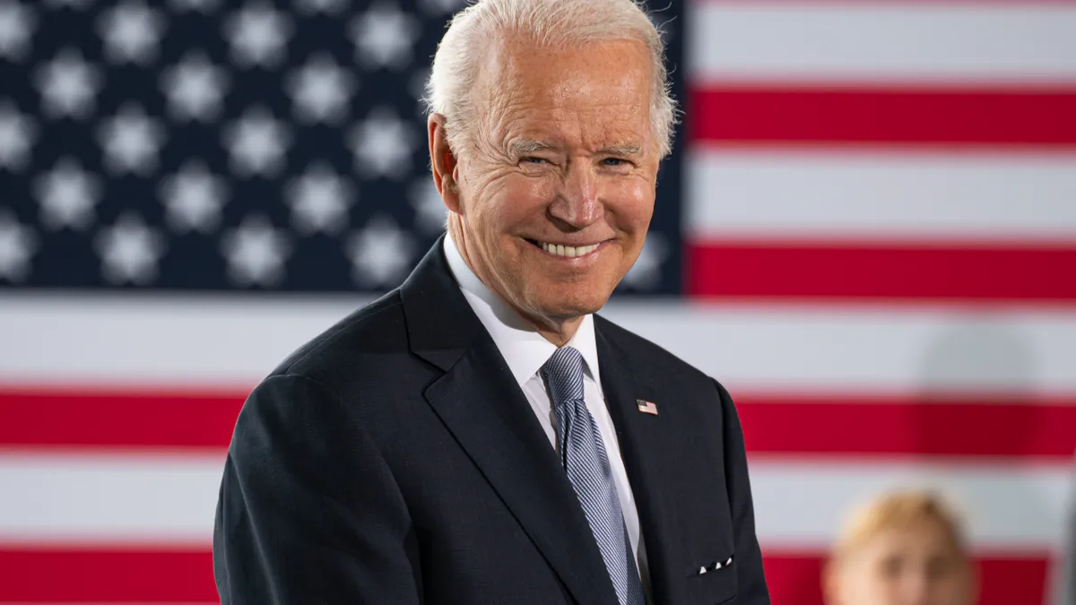 Joe Biden smiles while delivering remarks.