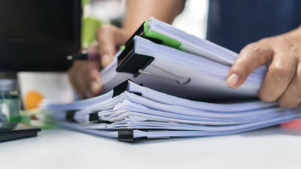 A person searches through paperwork in an office.