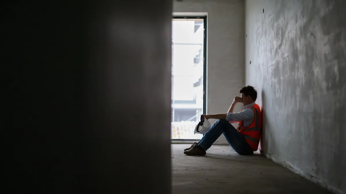 A construction worker sits alone at a jobsite.