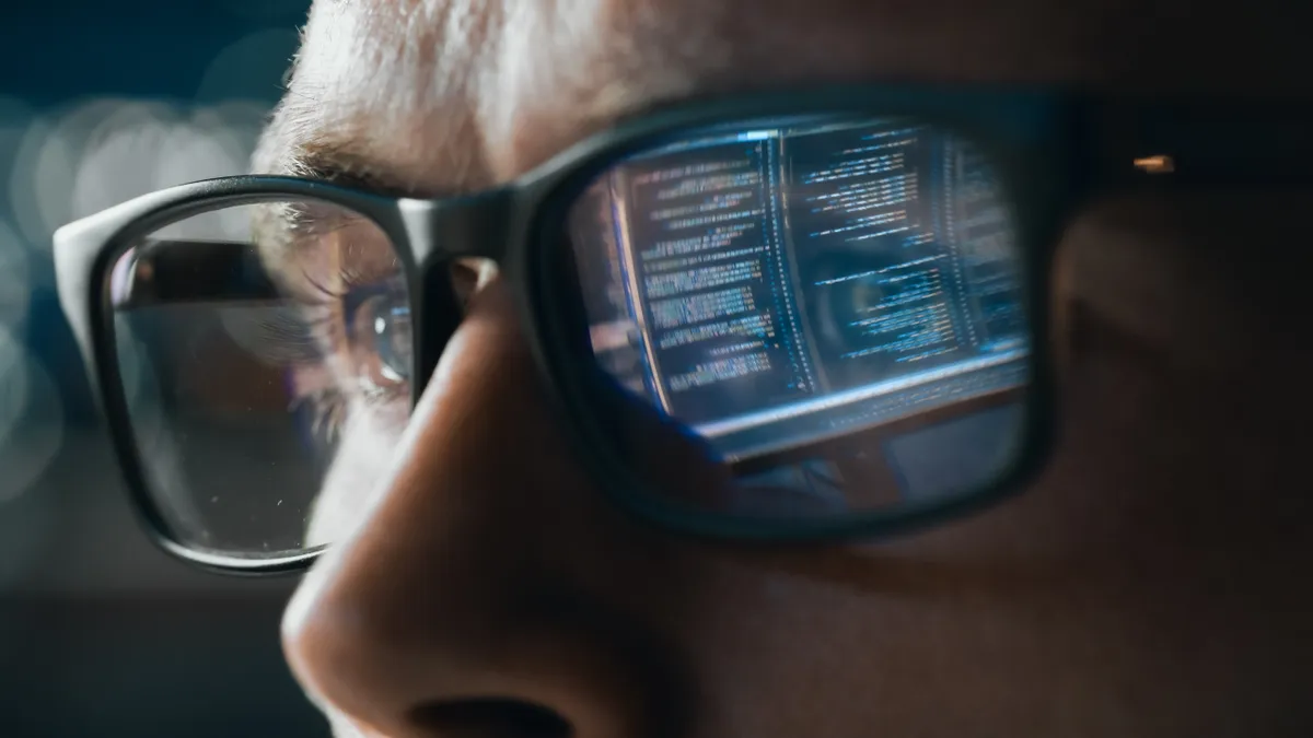 Close-up Portrait of Software Engineer Working on Computer, Line of Code Reflecting in Glasses.