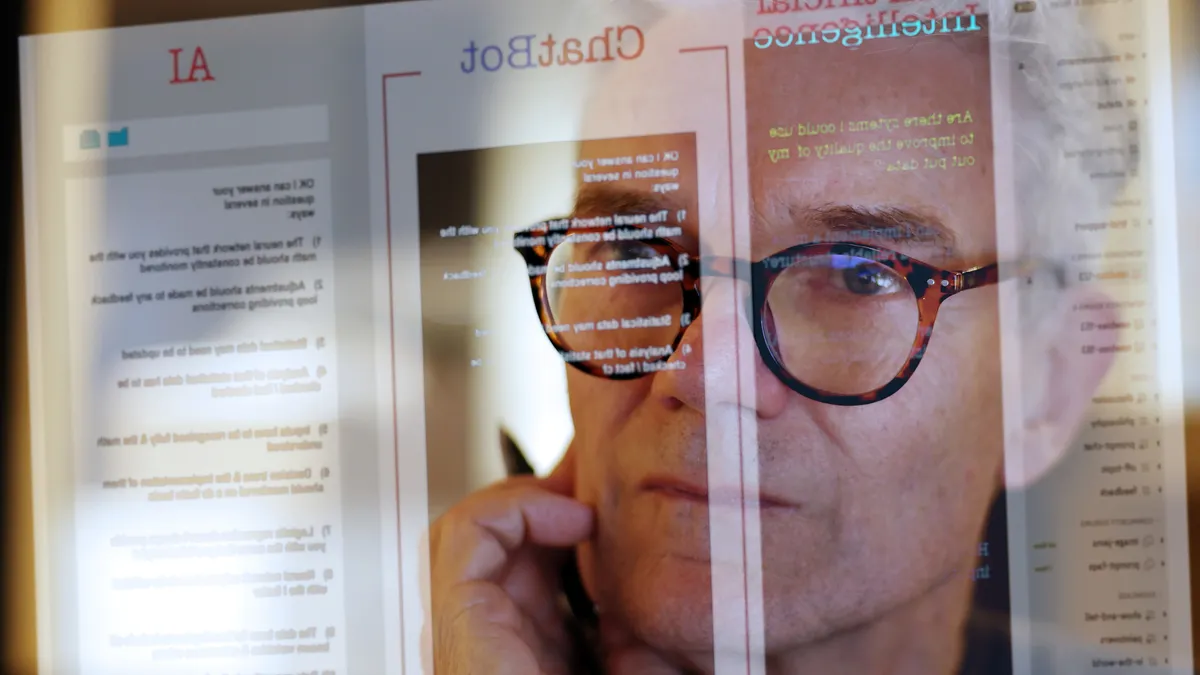 A mature man studying a see-through computer monitor that’s displaying text provided by an AI (artificial intelligence) chatbot.