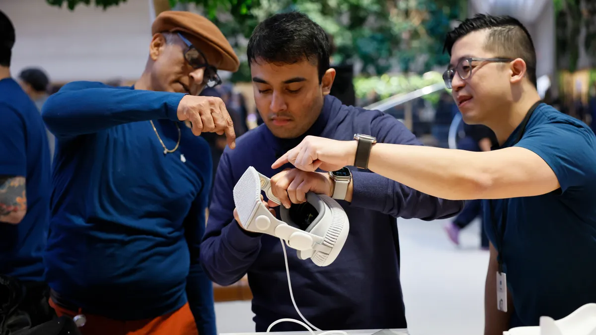 Individuals look at an Apple Vision Pro headset.