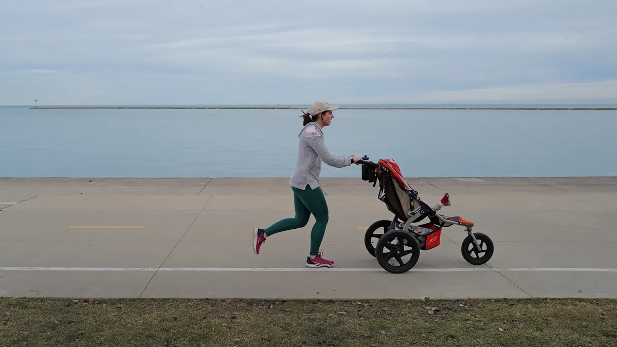 A jogger is pushing a child's stroller along the Chicago lakefront.
