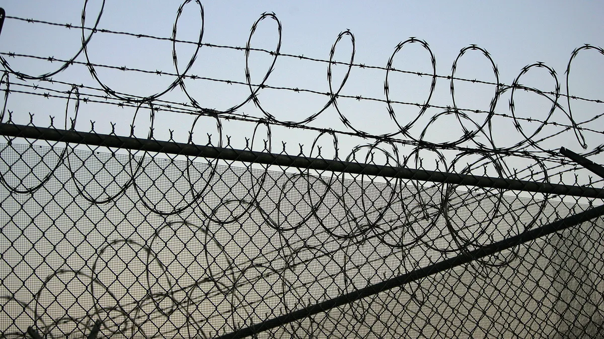 Barbed wire sits atop a chain-link fence.