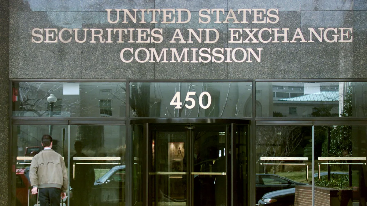 The front of the agency headquarters, reading "United States Security and Exchange Commission" and the number 450 as a man walks in a glass door at the bottom left of the frame.