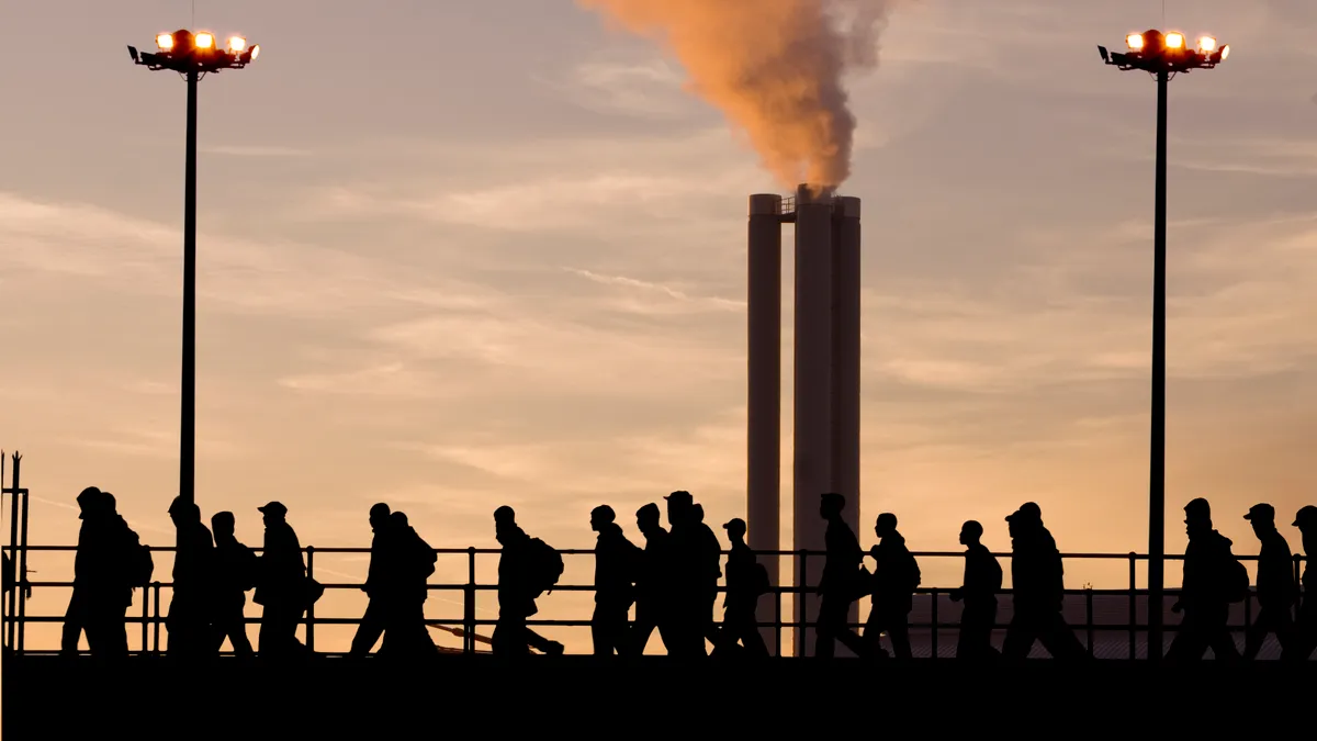 A group of industrial workers walk across a bridge.