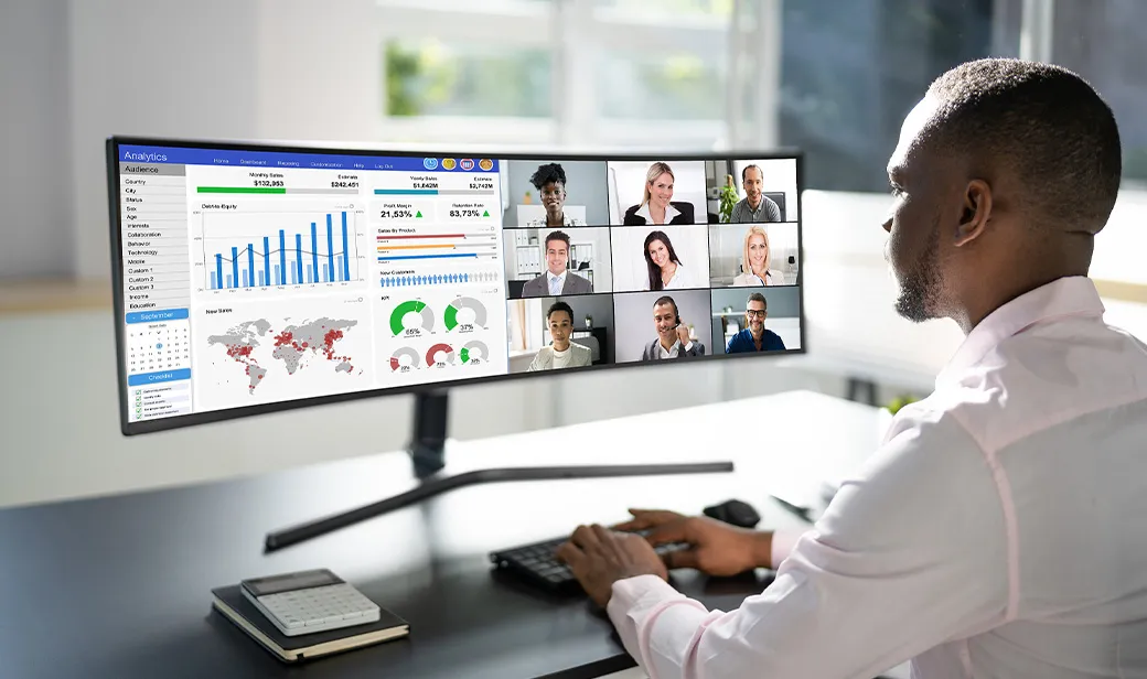 A person working on a very wide monitor screen at their desk.