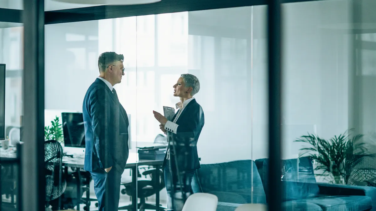 Two colleagues discuss a business matter in the office